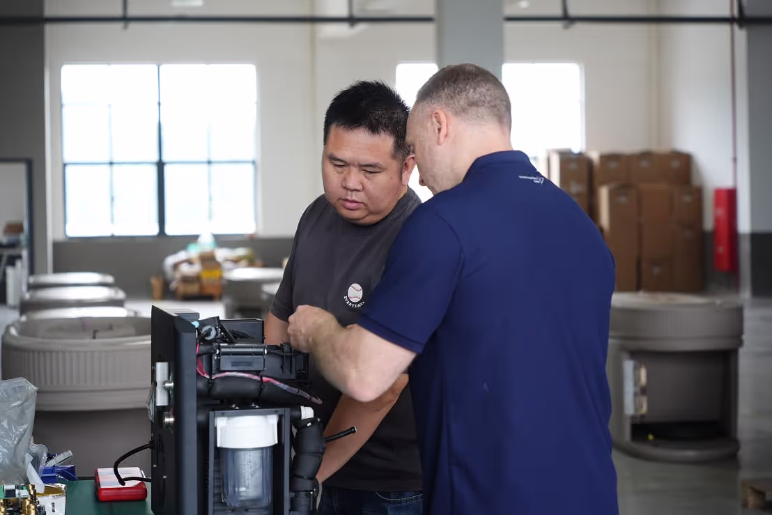 A Sourcing Allies engineer and a factory technician working on a unit